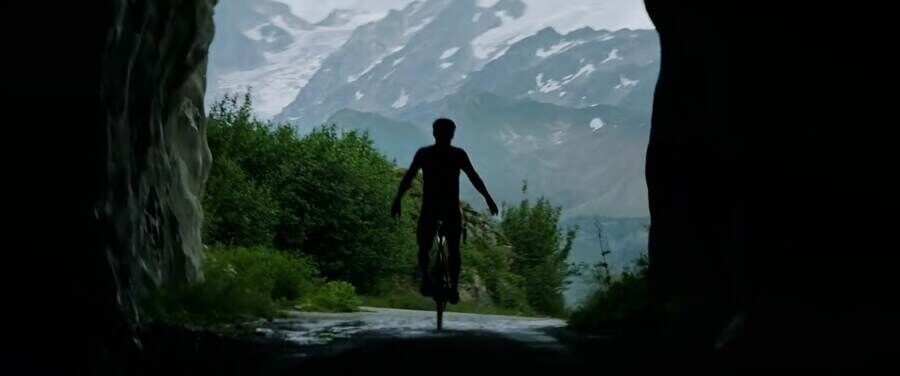Un cycliste filmé de dos à la sortie d'un tunnel, Émosson